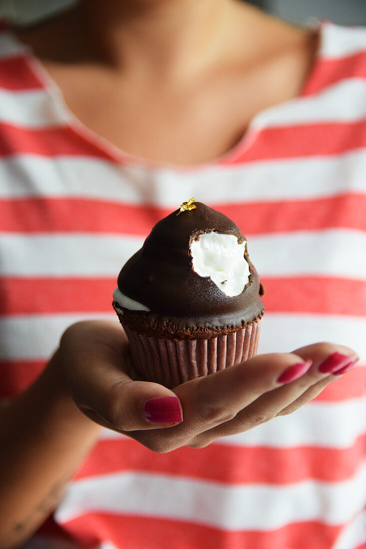 A woman holding a chocolate marshmallow cupcake