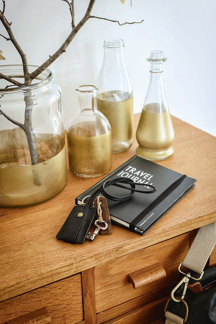 Note book and key chain in front of bottles painted gold