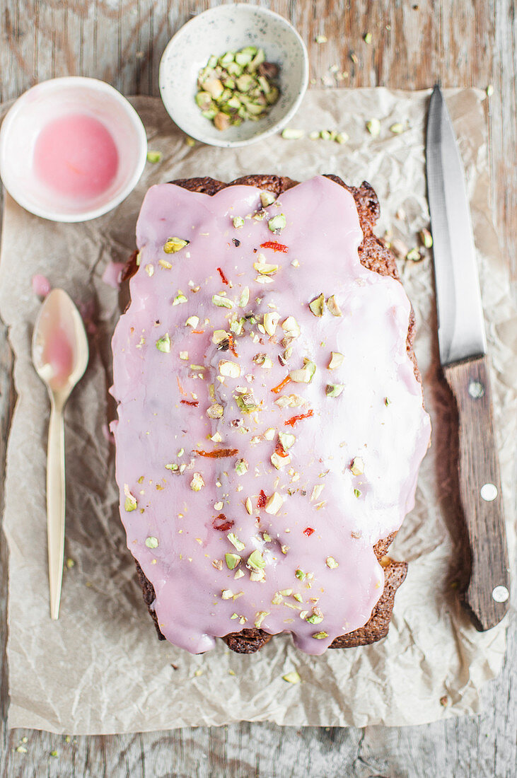 Carrot cake topped with pink icing and chopped pistachios