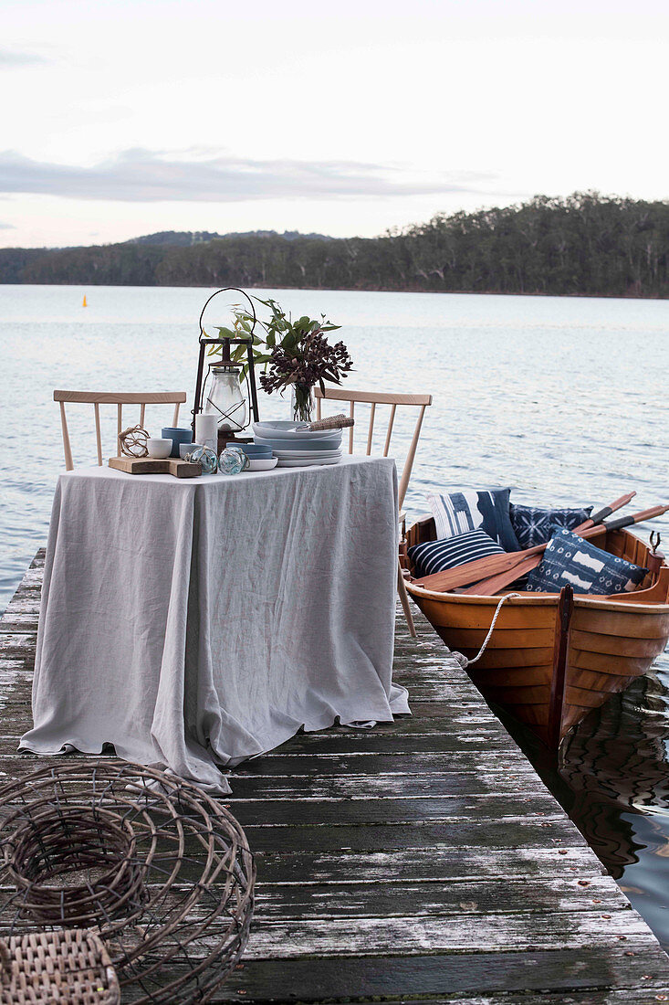 Gedeckter Tisch auf einem Steg und Boot auf einem See