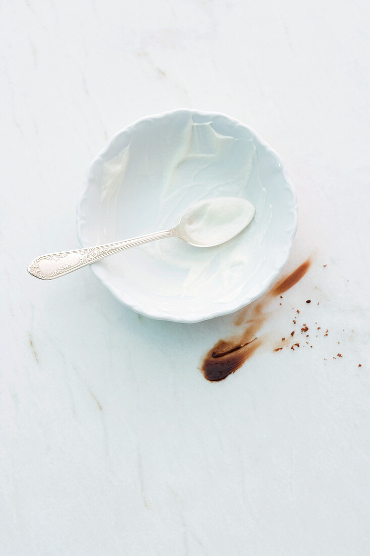 The remains of cream in a bowl next to smear of chocolate glaze
