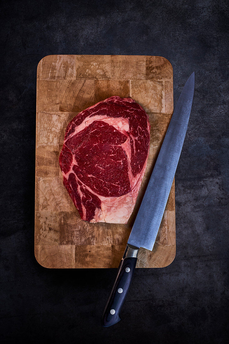 Raw beefsteak on a chopping board with a knife