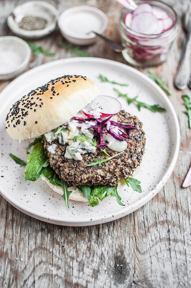 Vegetarischer Pilz-Hirse-Burger mit Gorgonzola, Meerrettichsauce, Rotkohl und Radieschen