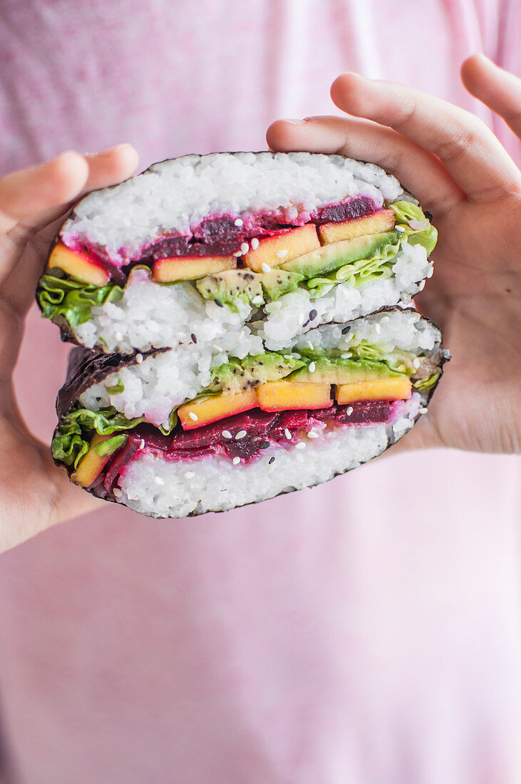 Rainbow vegan onigirazu filled with lettuce, avocado, mango and roasted beetroot