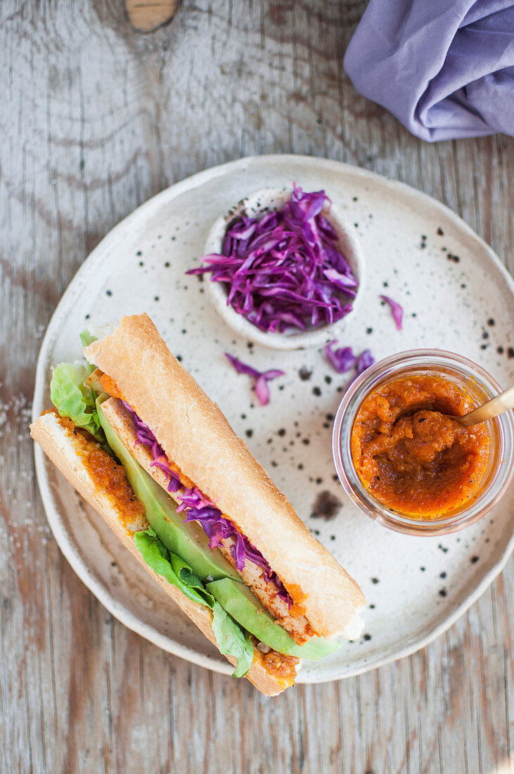 Veganes Sandwich mit Tofu, Avocado, Rotkohl und Karotten-Habanero-Sauce