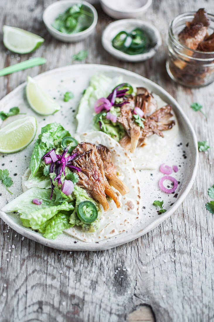 Vegan tacos with oyster mushrooms, jalapeno, guacamole, lettuce and pickled red onion