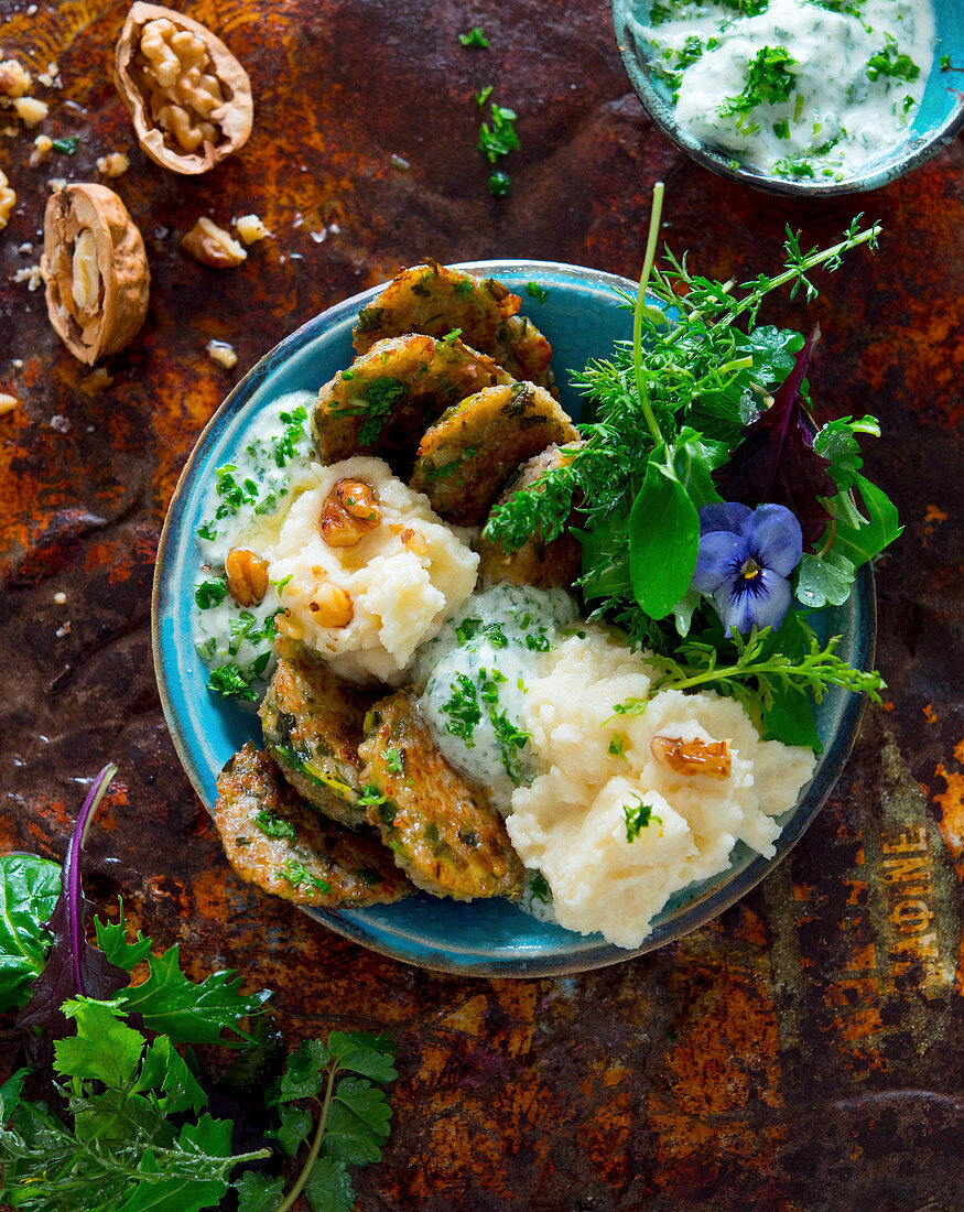 Bowl mit Kartoffelplätzchen, Pastinakenpüree, Petersilienjoghurt, Gartensalat und Walnüssen