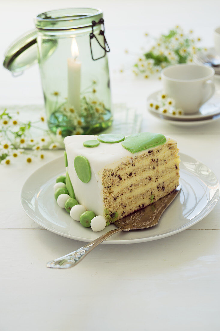 Stück Buttercremetorte mit Fondant, Kamillenblüten und Kerze