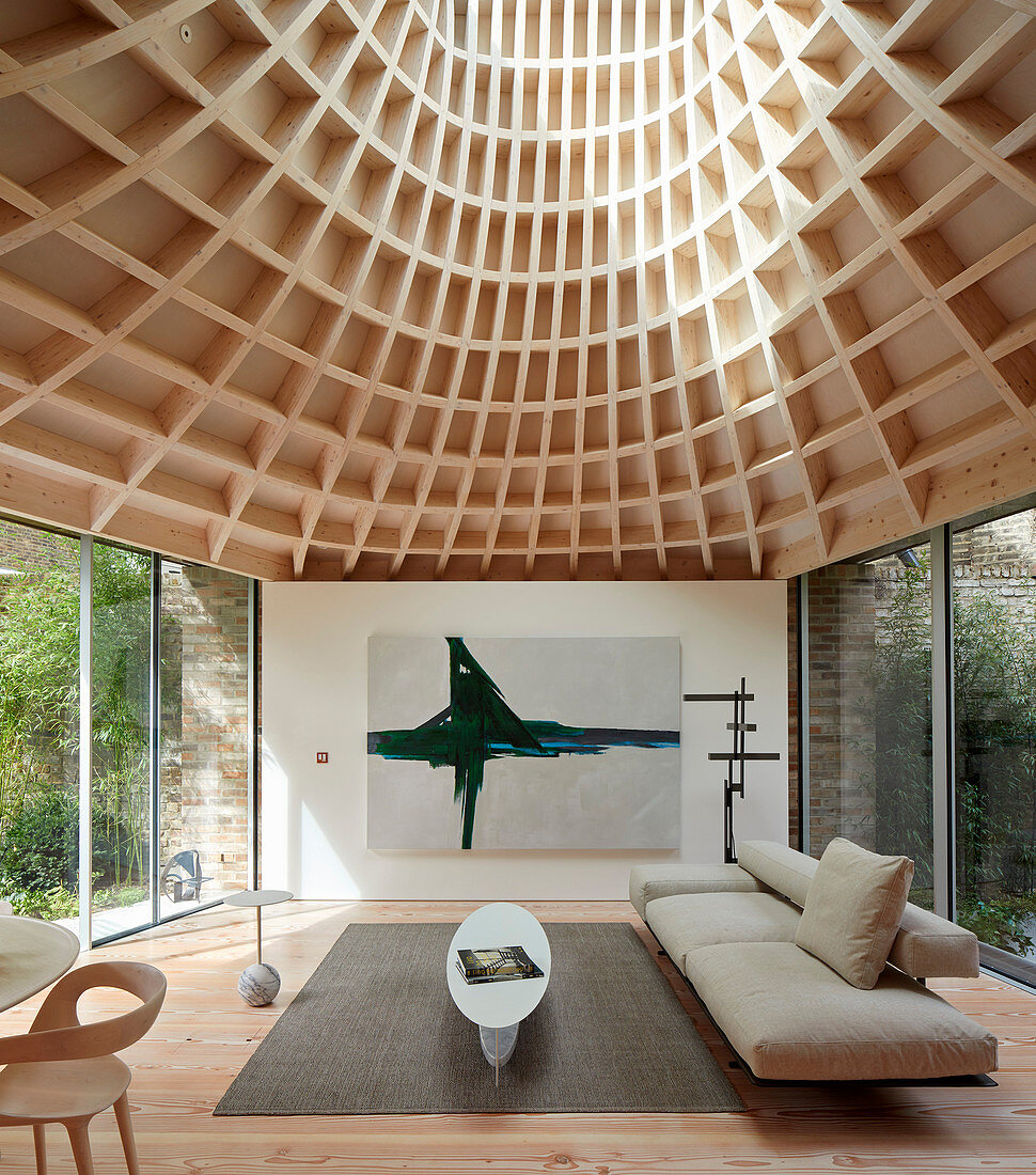 Minimalist living room in modern extension with glass walls and funnel-shaped roof