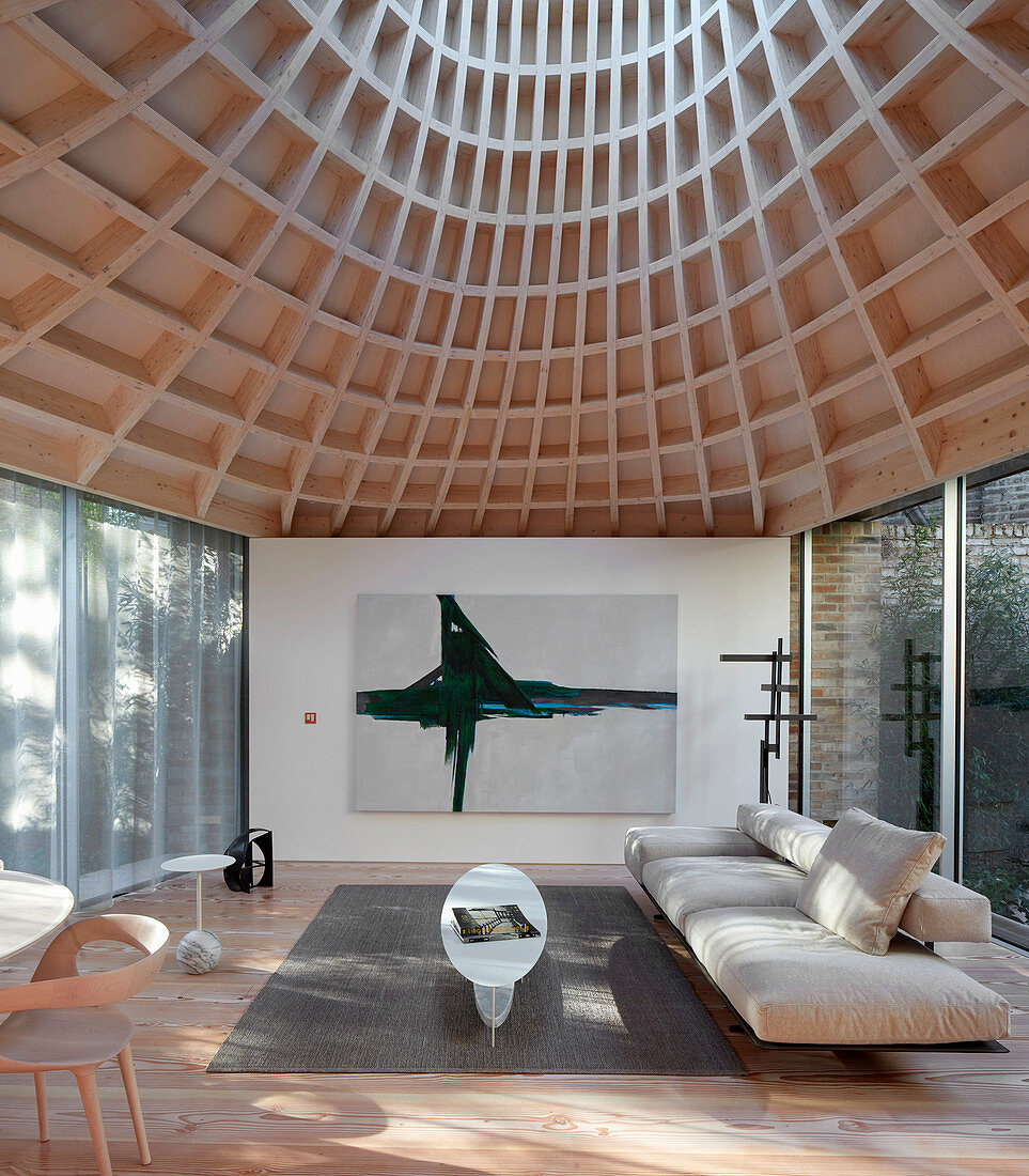 Minimalist living room in modern extension with glass walls and funnel-shaped roof