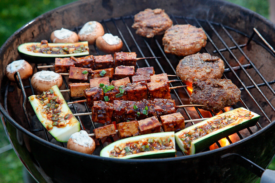 Vegetables, mushrooms, tofu skewers and lamb meatballs on a barbecue