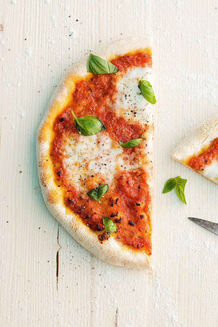 Halbe Pizza mit Tomaten, Mozzarella und Basilikum