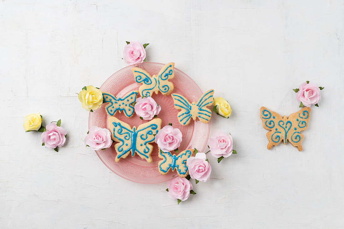 Schmetterlingskekse mit Zuckerschrift und Papierrosen