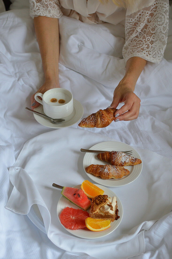 Frühstück im Bett mit Croissants, Obst und Kaffee