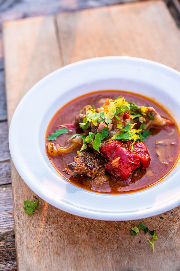 A portion of braised cuts of meat with bacon, onions and pepper