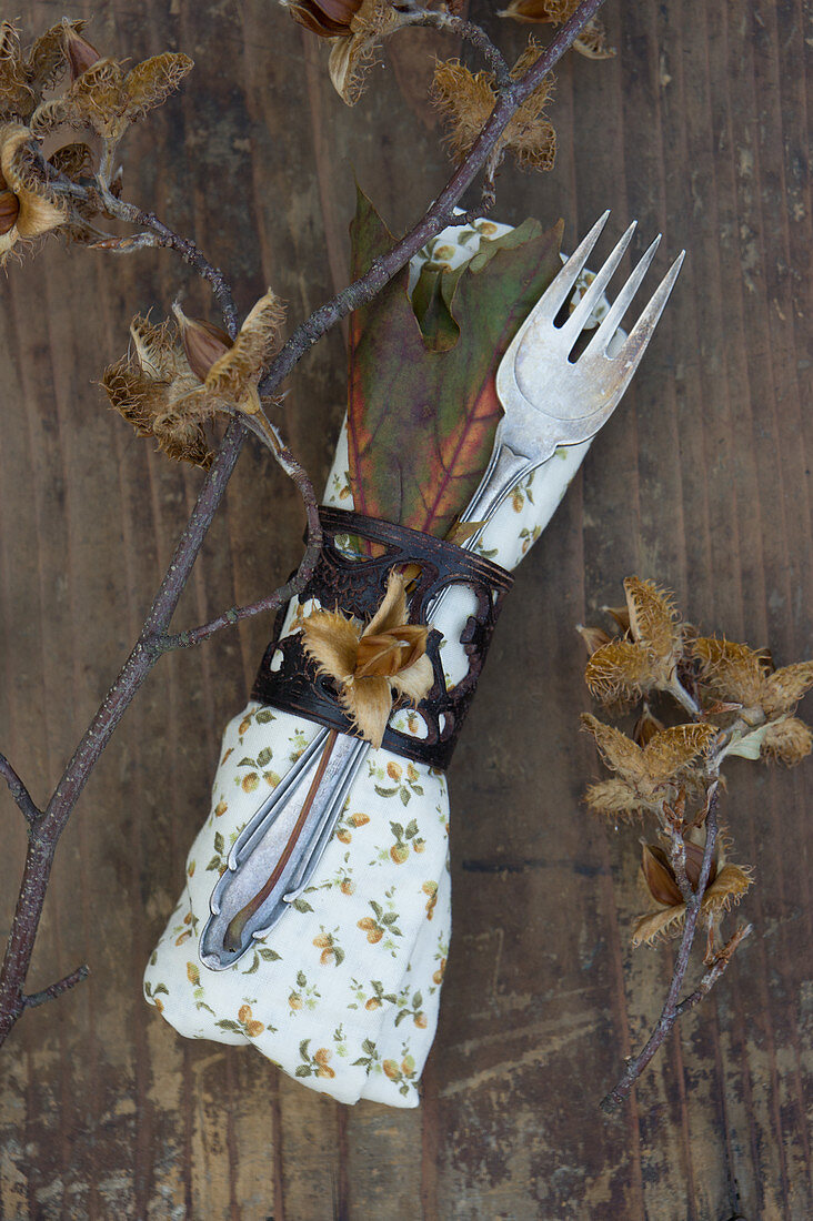 A napkin with cutlery, beechnuts and autumnal leaves