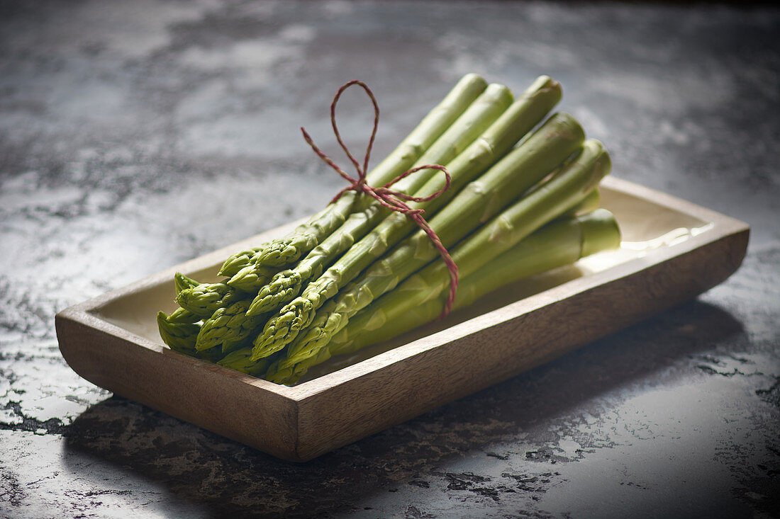 Ein Bund grüner Spargel auf Holzschale