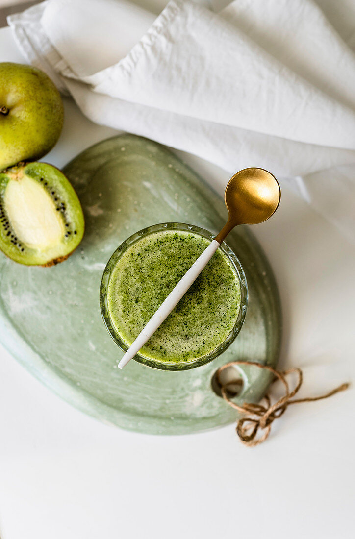 Healthy green smoothie on stone table of spinach, apple avocado and kiwi with lemon juice