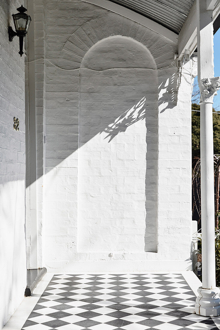 Entrance area with column-supported veranda and black and white checkerboard floor