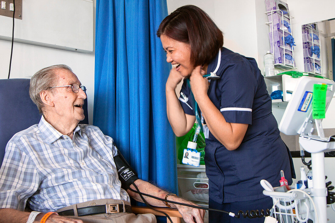 Elderly patient laughing with hospital nurse