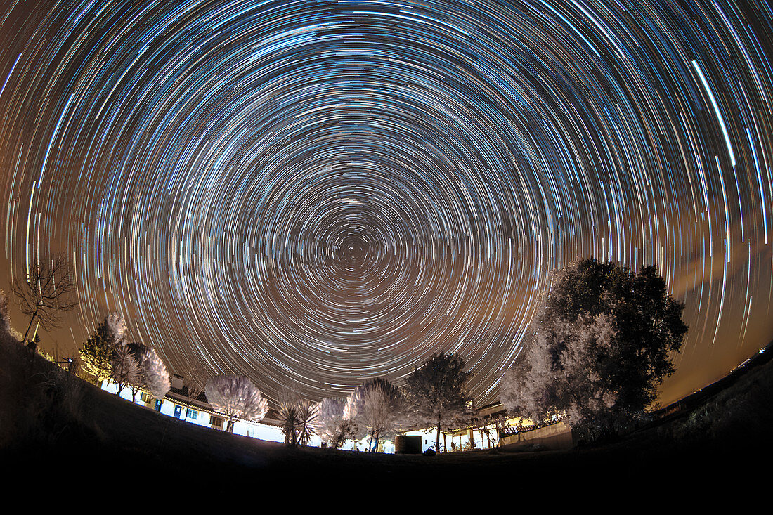 Star trails over rural hotel, time-exposure image