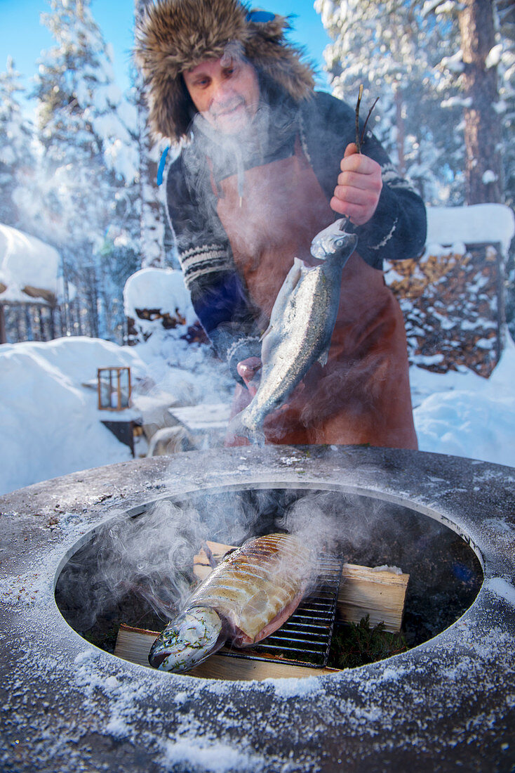 Wintergrillen: Mann beim Räuchern von Lachsforellen (Norwegen)