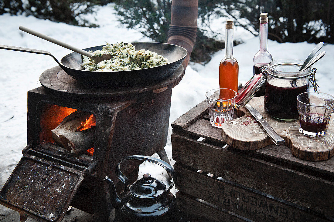 A winter barbecue with pans on a rustic wood-fired oven in the snow