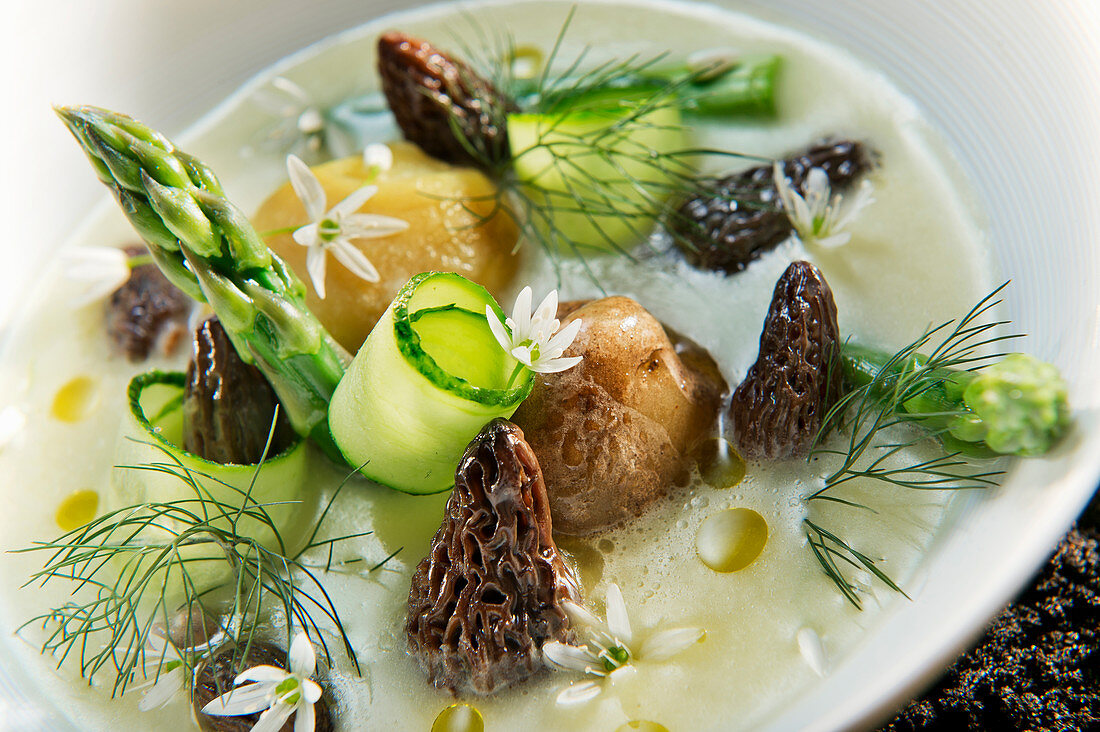 Natural cuisine: cream of potato soup with morel mushrooms, asparagus and edible flowers