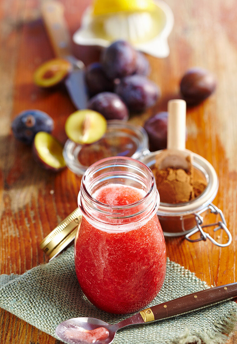 Homemade damson syrup in a jar with cinnamon and lemon