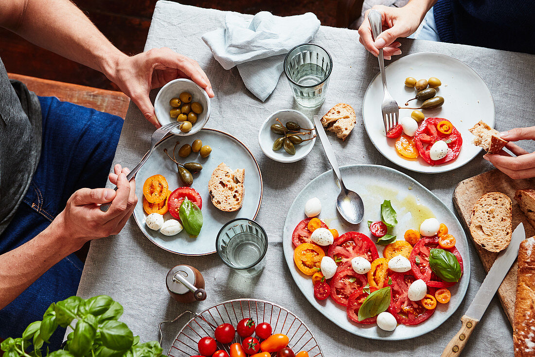 Paar isst Tomaten mit Mozzarella, Oliven und Kapern