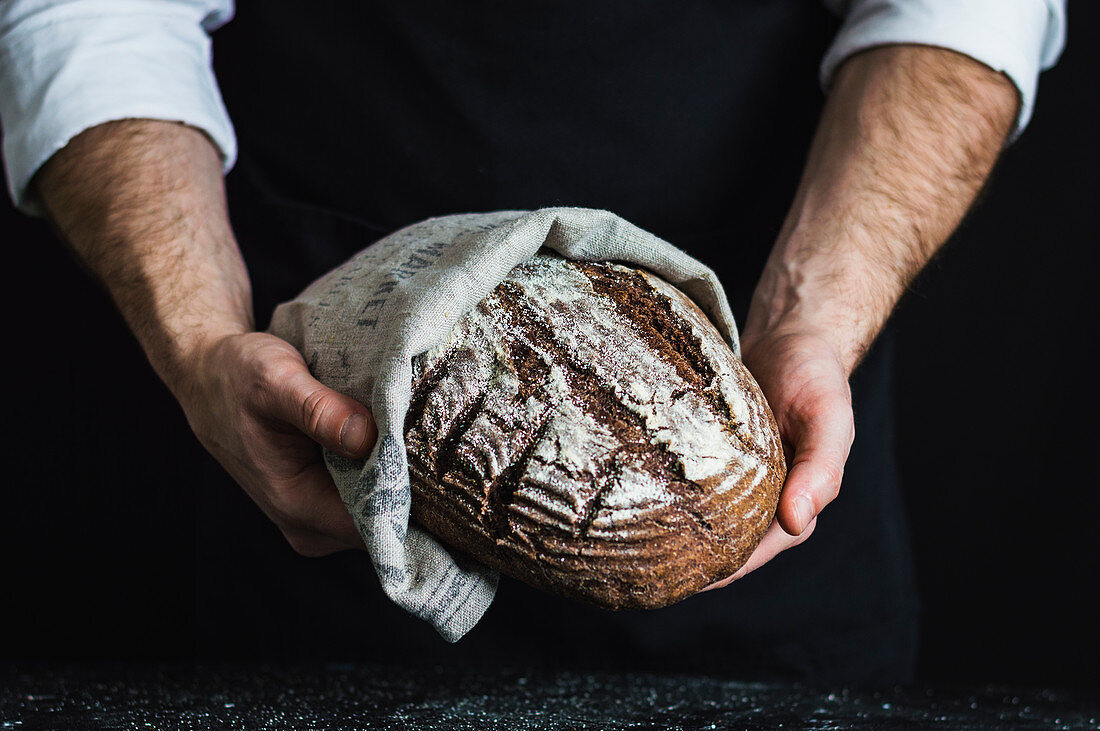 Man holding a spelt and wholewheat bread made with aronia (chokeberry) powder