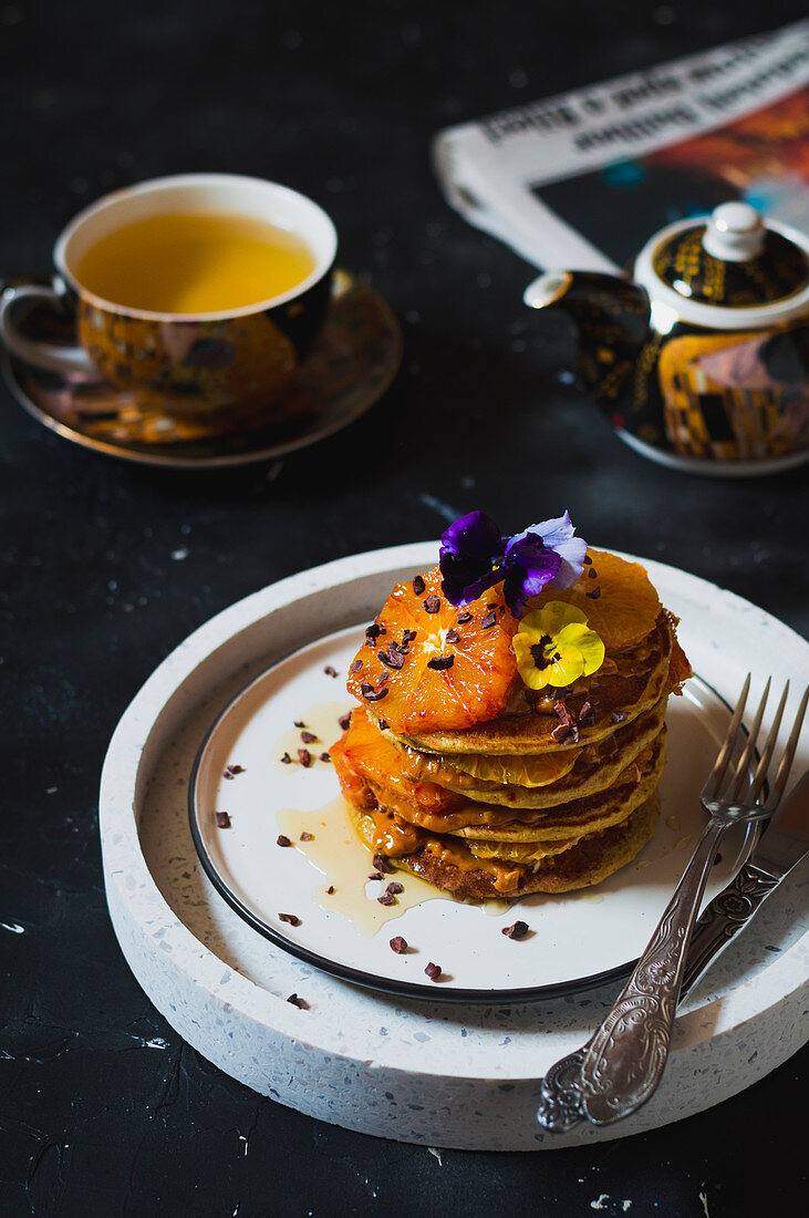 Haferpancakes mit Blutorangen, Honig, Kakaonibs und Essblüten zu einer Tasse Tee