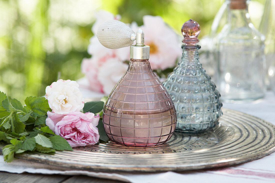 Handmade perfume in vintage perfume bottles on tray with roses