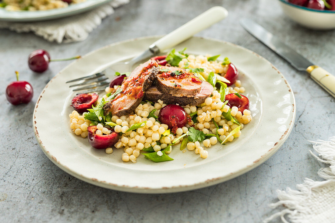 Couscous salad with fresh sweet cherries and fried duck breast