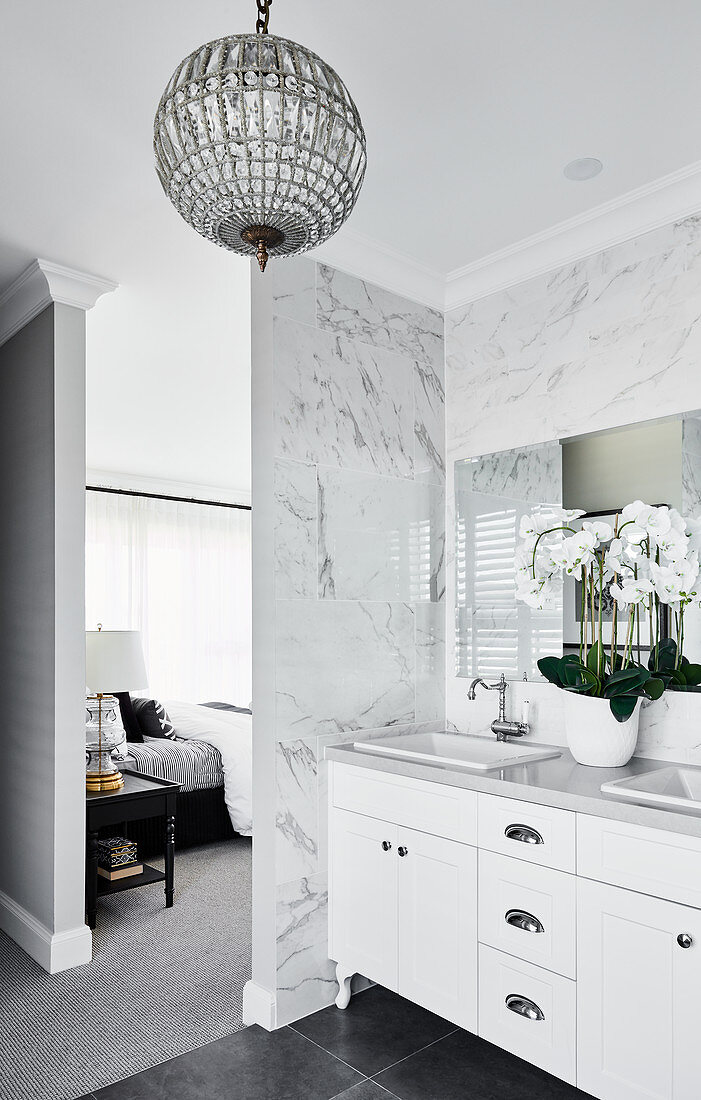 Washstand in ensuite bathroom with marble tiles and crystal lamp