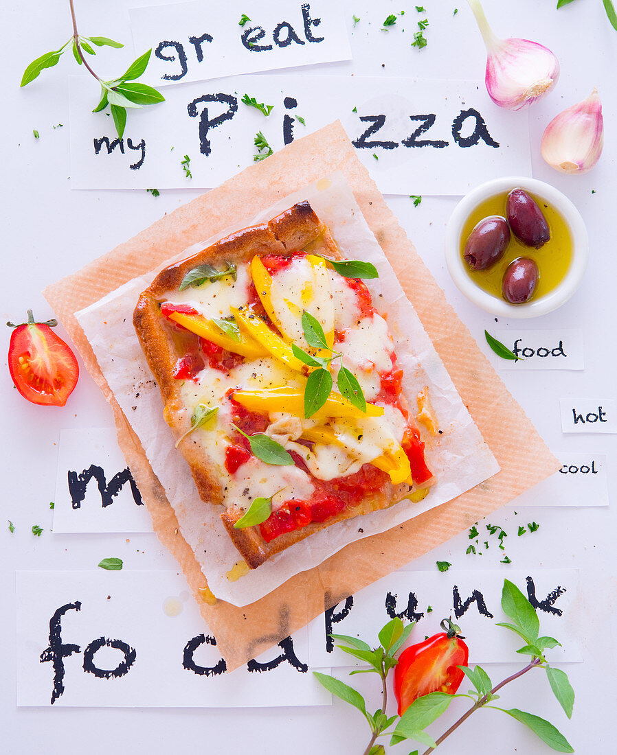 Stück Pizza mit Paprika, Mozzarella und Basilikum