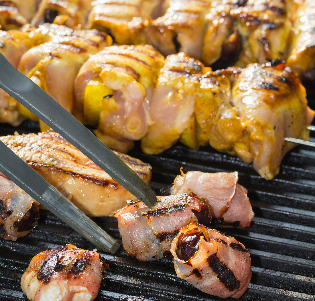 Dates in bacon and meat kebabs on a barbecue