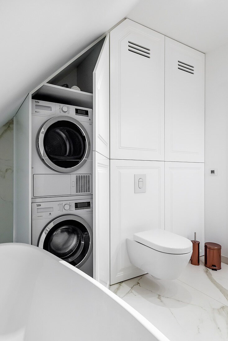 Washing machine and tumble dryer in fitted cupboard in elegant bathroom