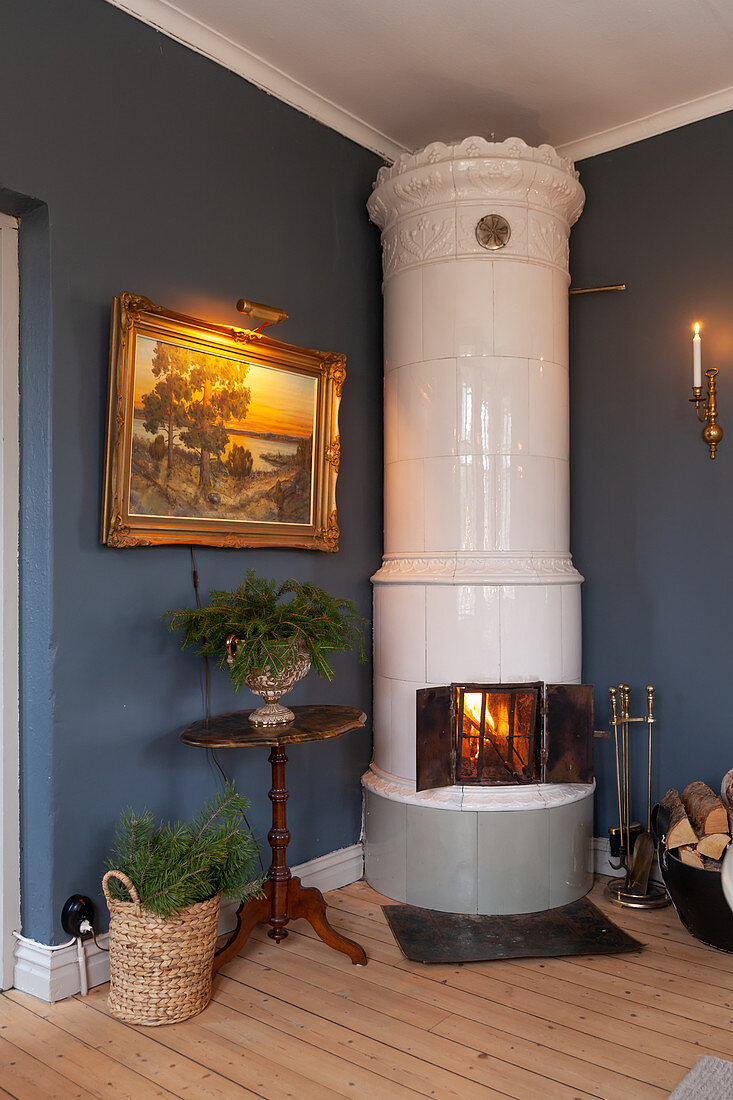 Cylindrical, Scandinavian, tiled stove in corner next to antique landscape painting