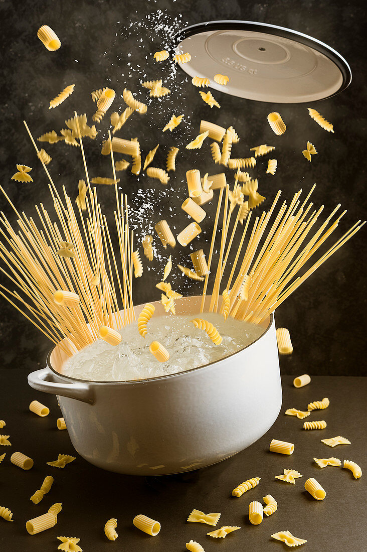 Various types of pasta falling into boiling water