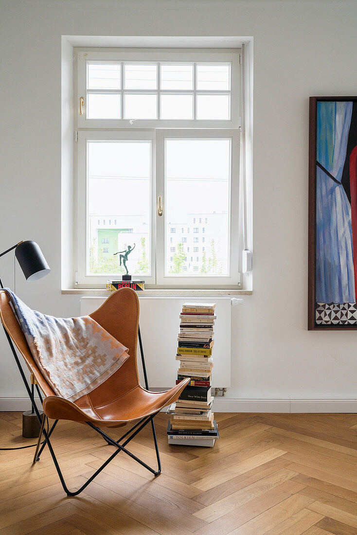 Butterfly Chair, standard lamp and stack of books in reading corner below period window