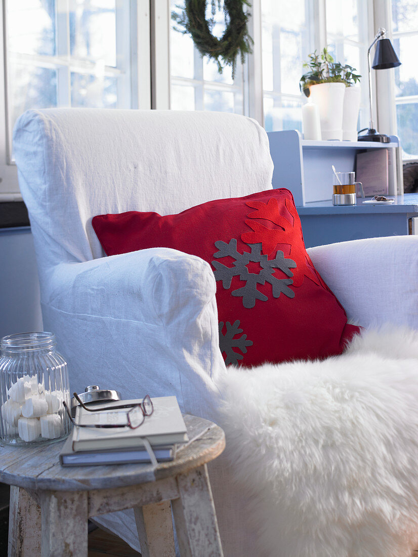 Red cushion with felt appliqué snowflakes on fur blanket on armchair