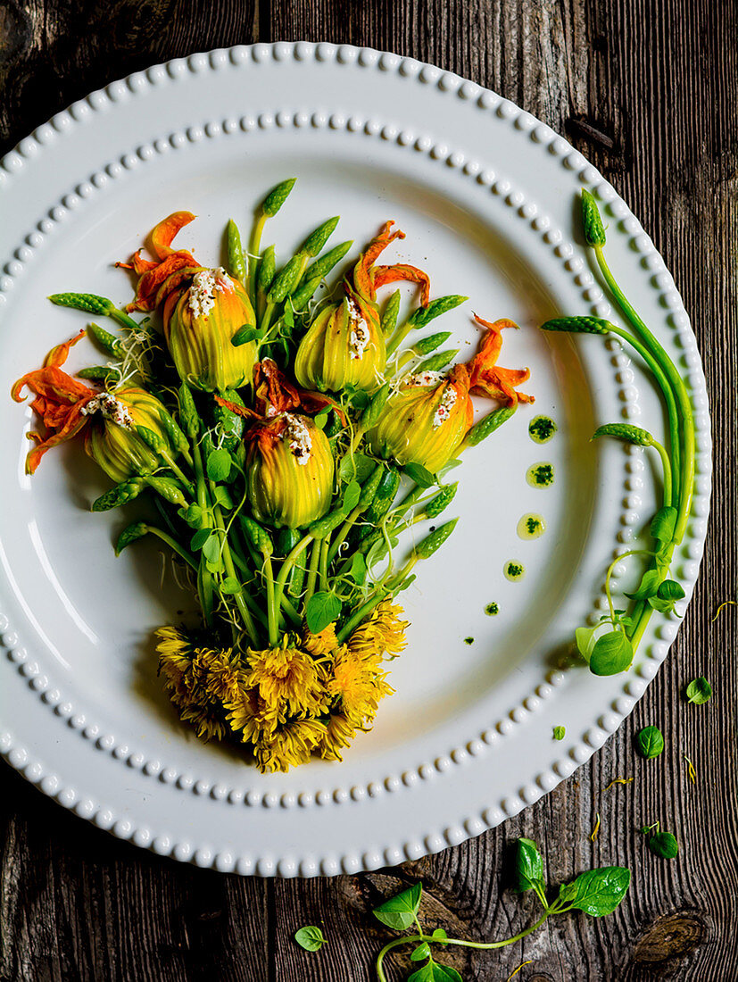 An arrangement of courgette flowers and wild asparagus on a plate