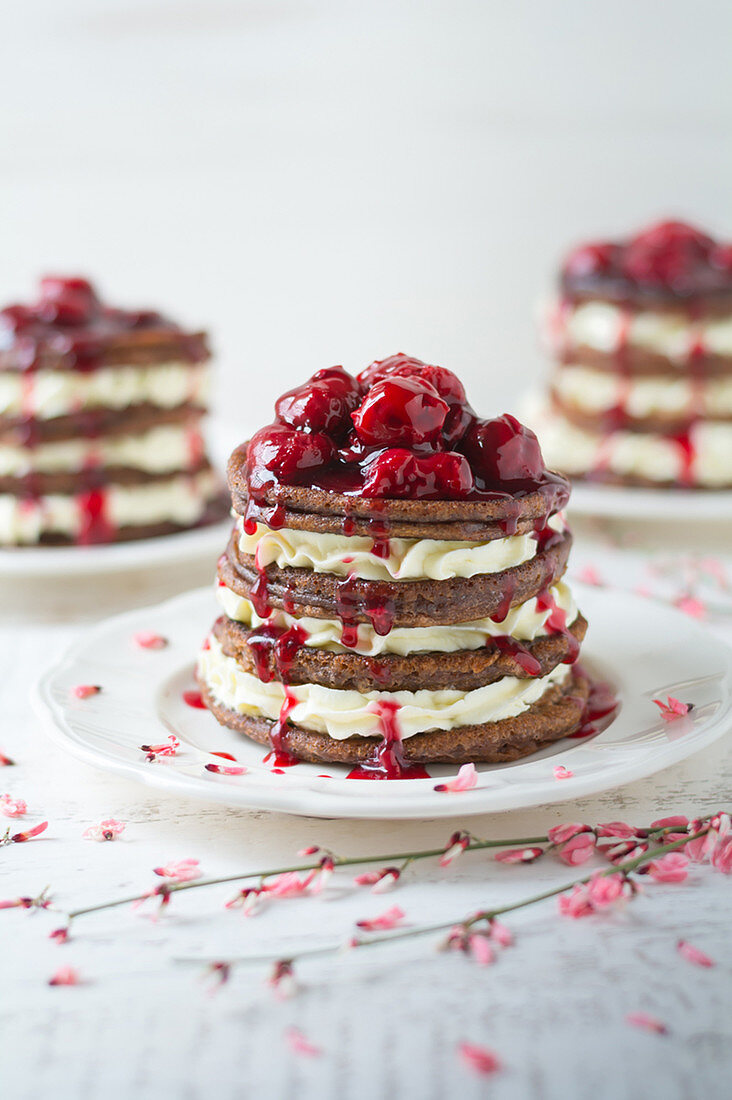 A stack of pancakes with cream and cherries