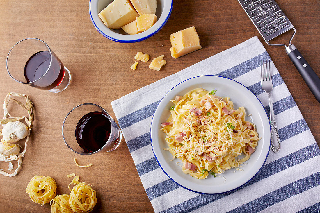 Homemade pasta Carbonara with parmesan cheese and a glass of red wine