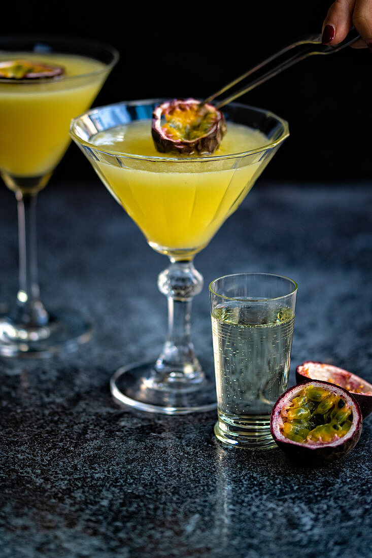 Slice of passion fruit being added to martini glass of Porn Star Martini cocktail