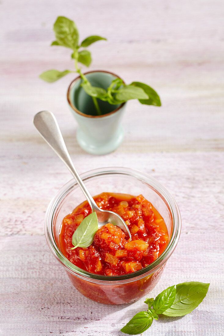 Pineapple and tomato chutney in a jar with fresh basil
