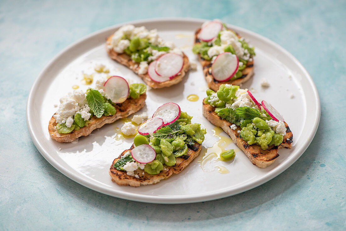 Broad bean bruschetta with feat cheese, mint, radish and olive oil