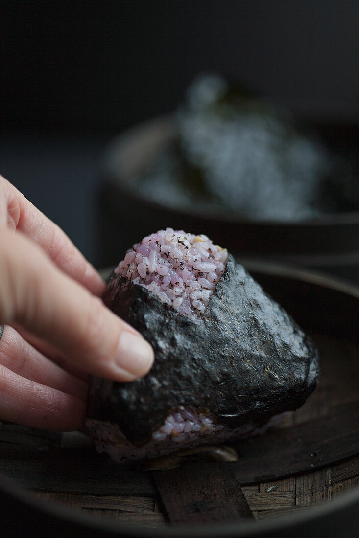 A hand holding onigiri with red shiso (Japan)
