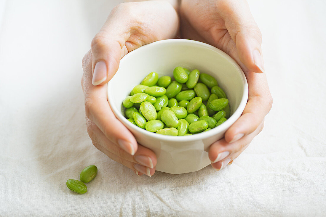 Female hands holding a bowl with edamame beans